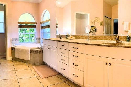 ein Badezimmer mit zwei Waschbecken und einer Badewanne in der Unterkunft Relax with nature in our Waterfront 4 bedroom -HEATED POOL HOME-KING BED in Cape Coral