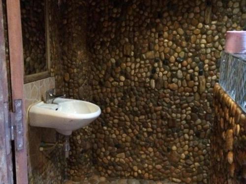 a bathroom with a stone wall with a sink at Tree Top Eco-Lodge in Banlung