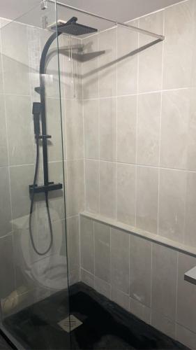 une douche avec une porte vitrée dans une salle de bain dans l'établissement Bord de mer Le Havre, au Havre