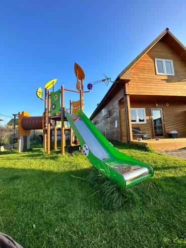 a playground in a yard with a green slide at Domki Krasne Morze in Mielenko