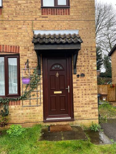 a brown door on the side of a brick house at Quiet Single bedroom with free parking, office desk &chair, free wifi in Harrowden