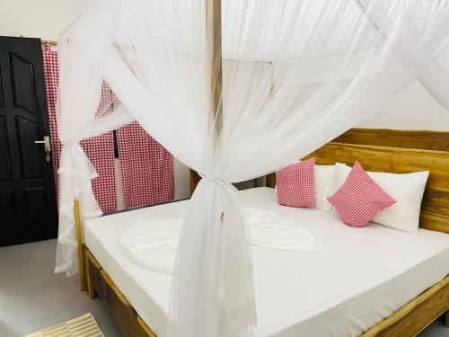 a bedroom with a canopy bed with pink and white pillows at Swiss kiss beach resort in Uppuveli