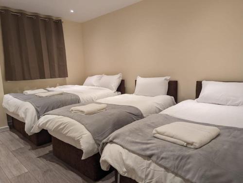 a room with three beds with pillows on them at Newly Launched Two Bedroom House By Den Accommodation Short Lets & Serviced Accommodation With Garden in London