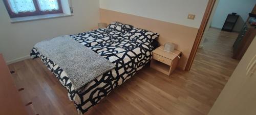 ein Schlafzimmer mit einem Bett mit einer schwarzen und weißen Decke in der Unterkunft Il Rifugio in Tarvis