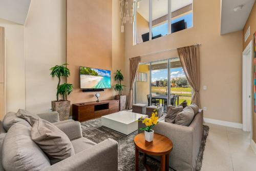a living room with two couches and a tv at 4 BR Home w/ Resort Amenities + 3 Mi to Disney in Orlando