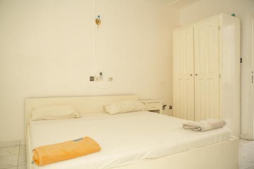 a white bedroom with a white bed and a door at Tahiti Hotel in Cotonou