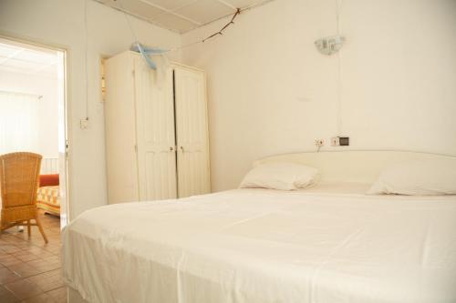 a bedroom with a white bed and a cabinet at Tahiti Hotel in Cotonou