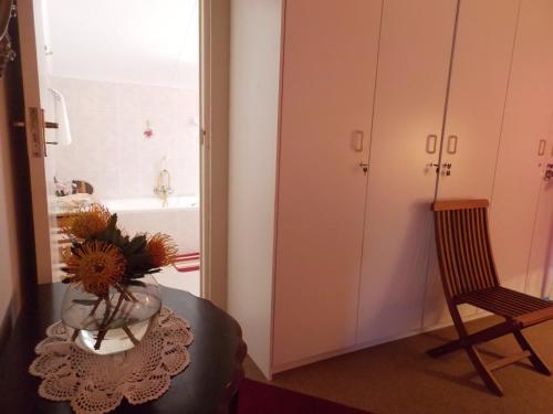 a bathroom with a table with a vase of flowers at Avondsrus Guesthouse in Bettyʼs Bay