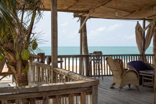 a porch with chairs and a table and the ocean at Tahiti Hotel in Cotonou