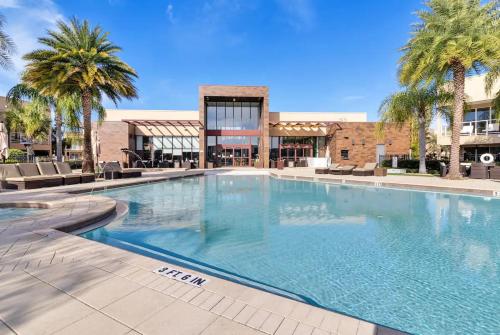 a large swimming pool with palm trees and a building at 4 BR Home w/ Resort Amenities + 3 Mi to Disney in Orlando