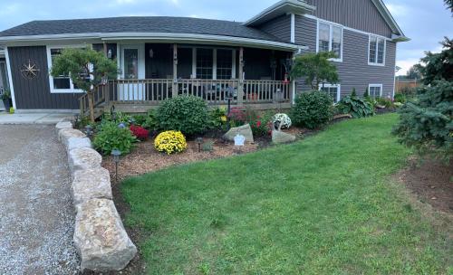 a house with a porch with flowers in the yard at MonJardin Bed and Breakfast in Port Burwell