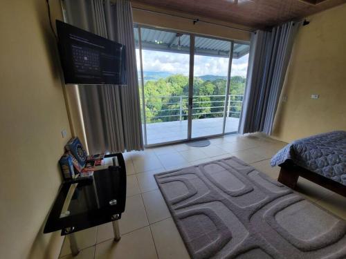 1 dormitorio con cama, TV y balcón en Suite Frente a la Cascada, en Tierras Morenas