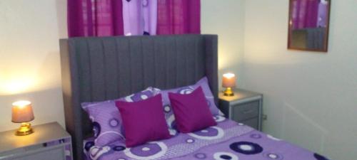 1 dormitorio con cama morada y almohadas moradas en Maria e Nicola en Jarabacoa