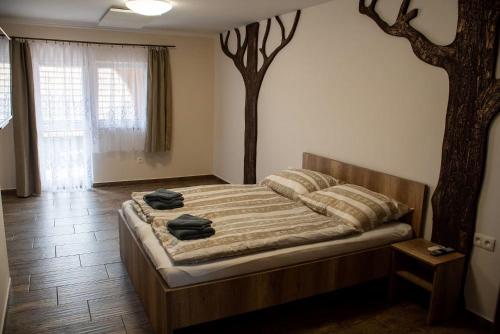 a bedroom with a bed with a tree on the wall at Scarlett Pension & Restaurant in Veľký Meder