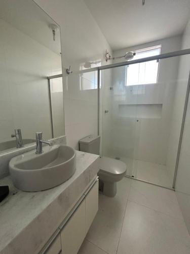 a white bathroom with a sink and a toilet at Apartamento inteiro com garagem em Diamantina/MG in Diamantina