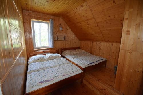 two beds in a wooden room with a window at Domyletnie Pobierowo Duży dom 140m2 z działką in Pobierowo
