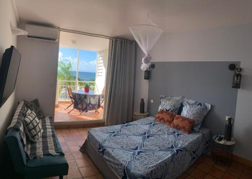 een slaapkamer met een bed en uitzicht op een patio bij La Fraîche Rosé in La Trinité