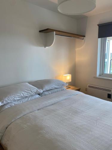 a bedroom with a white bed and a window at Apartment 6 @ Clifden Bay Apartments in Clifden