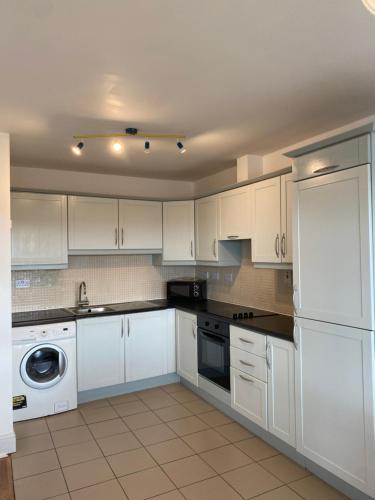 a white kitchen with white cabinets and a dishwasher at Apartment 6 @ Clifden Bay Apartments in Clifden