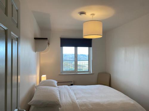 - une chambre avec un lit blanc et une fenêtre dans l'établissement Apartment 6 @ Clifden Bay Apartments, à Clifden