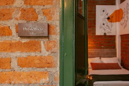 una habitación con una pared de ladrillo con un cartel. en Botánica Casa Hotel en Medellín