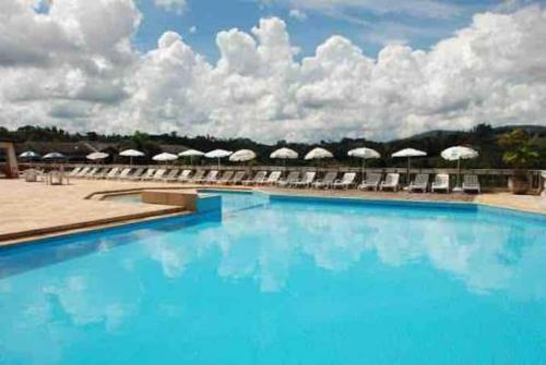 a large blue swimming pool with chairs and umbrellas at Piemonte Flat Serra Negra in Serra Negra