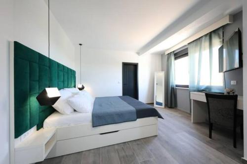 a bedroom with a bed with a green headboard at Boutique Residence Cosmopolis in Bibinje