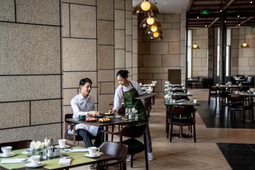 two people sitting at a table in a restaurant at Crowne Plaza Vinh Yen City Centre by IHG in Yen