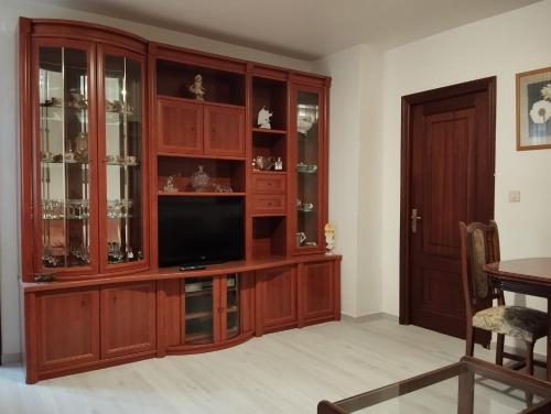 una sala de estar con TV en un centro de entretenimiento de madera en Apartamento céntrico Prado Blanco, en Finisterre