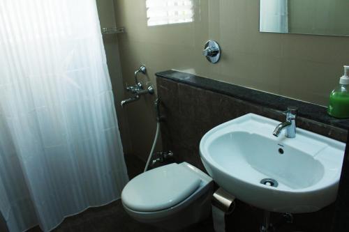 a bathroom with a white sink and a toilet at Aashiyana Inn in Nashik