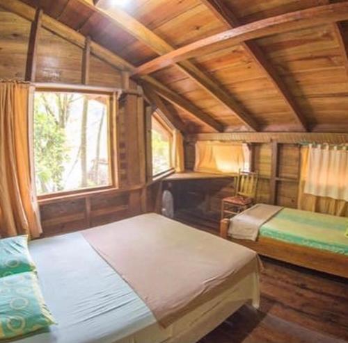 1 dormitorio con 2 camas en una habitación de madera en Jungle River Lodge en La Ceiba