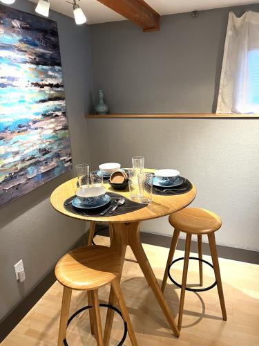 a dining room table with two stools and a painting at Bell In The Woods B&B in Seward