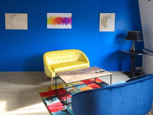 un salon avec une chaise jaune et une table dans l'établissement La note Bleue, Fécamp Bord de mer, à Fécamp