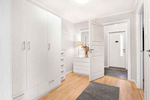 a white room with a hallway with white cabinets at Cozy and central home near Oslo Gardermoen Airport in Eidsvoll