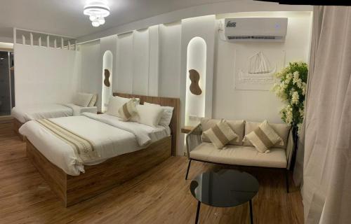 una camera con due letti e un divano di Sandy Heaven Maldives a Gulhi