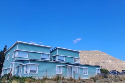 ein blaues Gebäude mit einem Hügel im Hintergrund in der Unterkunft Go Patagonia! in El Calafate