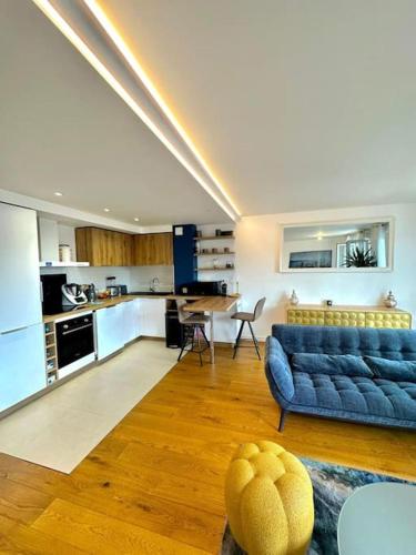 un salon avec un canapé bleu et une cuisine dans l'établissement Appartement vue sur Seine et parc, à Villeneuve-la-Garenne