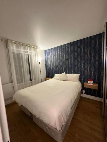 ein Schlafzimmer mit einem großen weißen Bett und einer blauen Wand in der Unterkunft Appartement vue sur Seine et parc in Villeneuve-la-Garenne