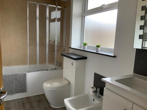 a bathroom with a toilet and a sink and a window at Beautiful 4 Bed House Free WIFI in Earley
