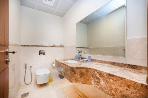 W łazience znajduje się umywalka, lustro i toaleta. w obiekcie Get Rooftop Pool at 2BR APT Near Mall Of Emirates 411 w Dubaju