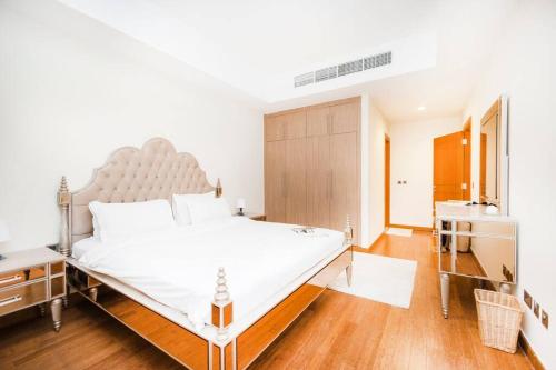una camera da letto con un grande letto bianco e pavimenti in legno di Get Rooftop Pool at 2BR APT Near Mall Of Emirates 411 a Dubai