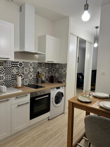 uma cozinha com armários brancos e uma máquina de lavar roupa em Apparemment cosy et chaleureux em Montauban