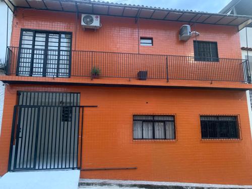 un bâtiment orange avec un balcon et une clôture dans l'établissement Casa de Temporada p 12 pessoas em Aparecida, à Aparecida