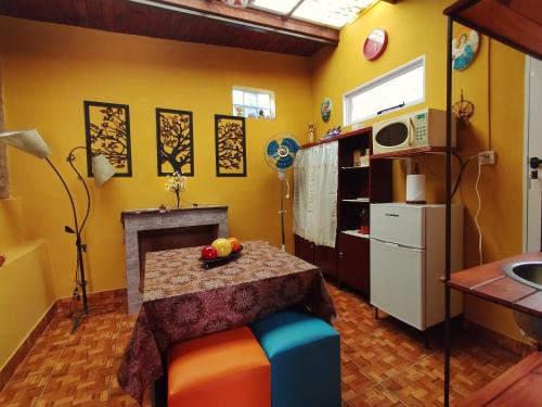 a kitchen with yellow walls and a table and a fireplace at Hospedaje Miguel in Maimará