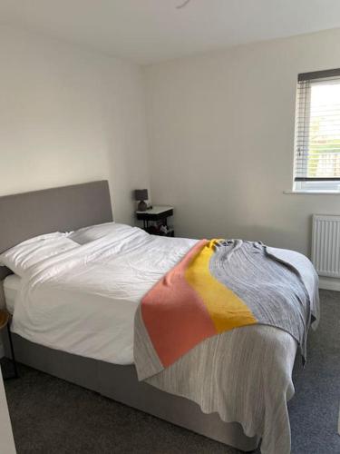 a bedroom with a bed with a colorful blanket on it at Cute house Littleover close to amenities hospital in Derby
