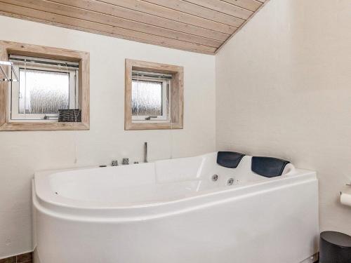 a white bath tub in a bathroom with two windows at 4 star holiday home in Ålbæk-By Traum in Ålbæk
