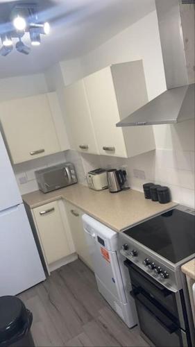 a kitchen with white cabinets and a stove top oven at Do not book having difficulty removing from page house is not bookable in Derby