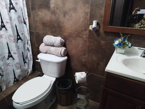 a bathroom with a toilet and a sink with towels at Jardin Imperial in Mexicali