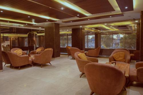 a waiting room with chairs and tables and windows at Granada Hotel in An Najaf