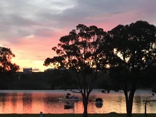 a sunset over a lake with boats in the water at The Wheelhouse - 2BR Waterfront Apt in town in Lakes Entrance